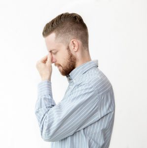 Profile of serious young man touching his nose bridge and thinking with eyes closed. Isolated side view on white background.